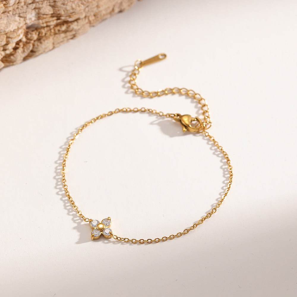 Gold chain bracelet with a crystal-set four-leaf clover charm and an adjustable link chain