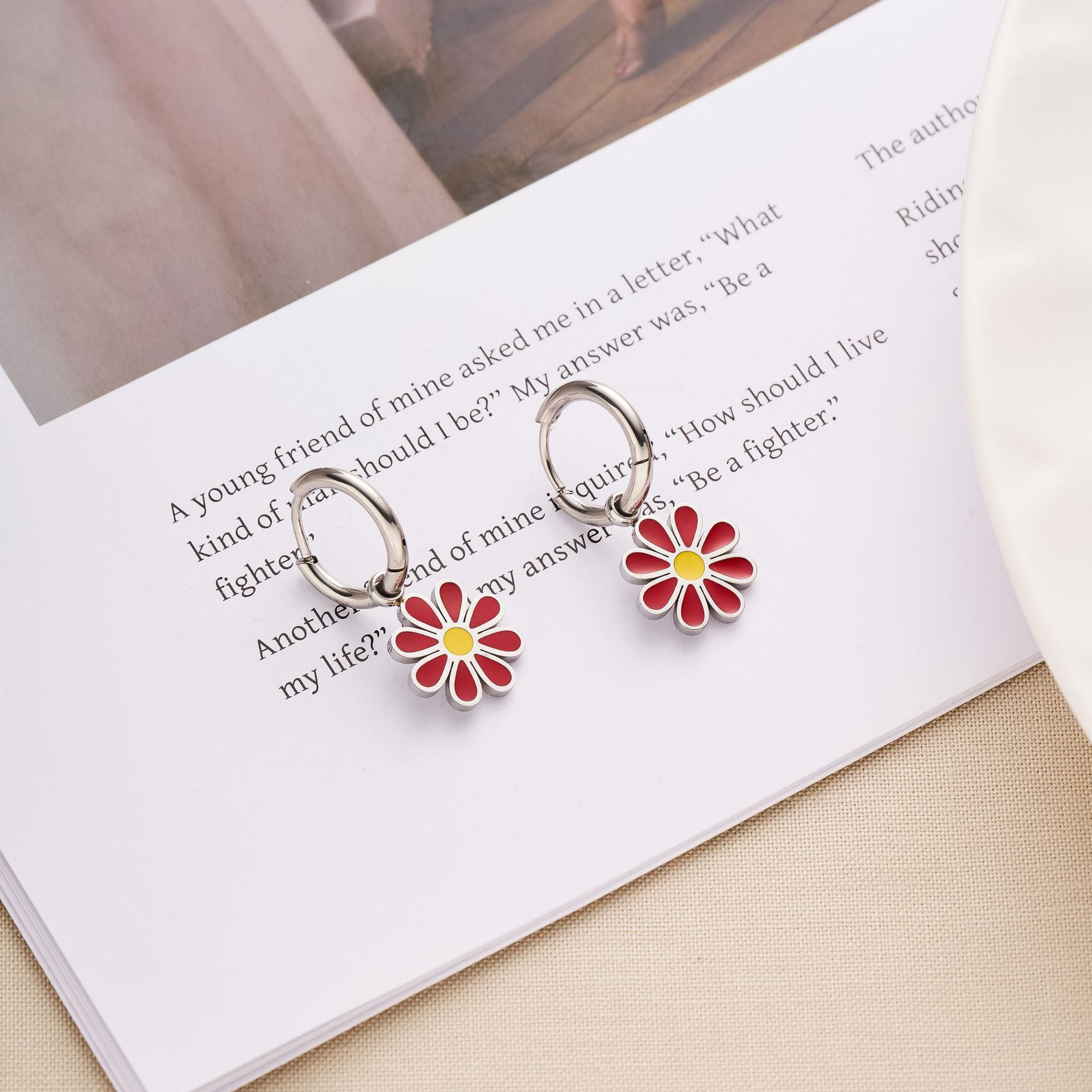 Red enamel daisy flower charms dangling from silver huggie hoop earrings