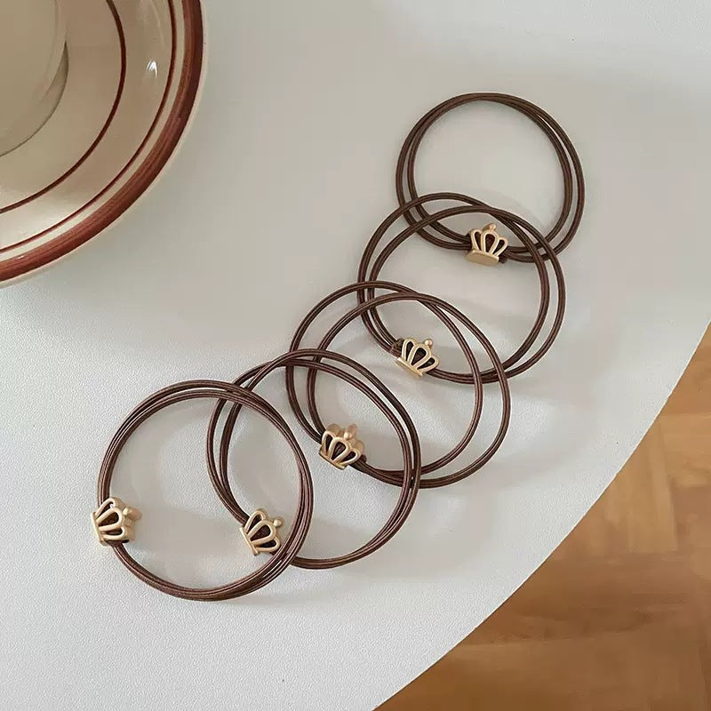 Brown cord hair tie with a small gold-tone crown charm