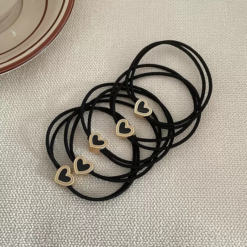 Black cord hair tie with a small gold-tone heart charm