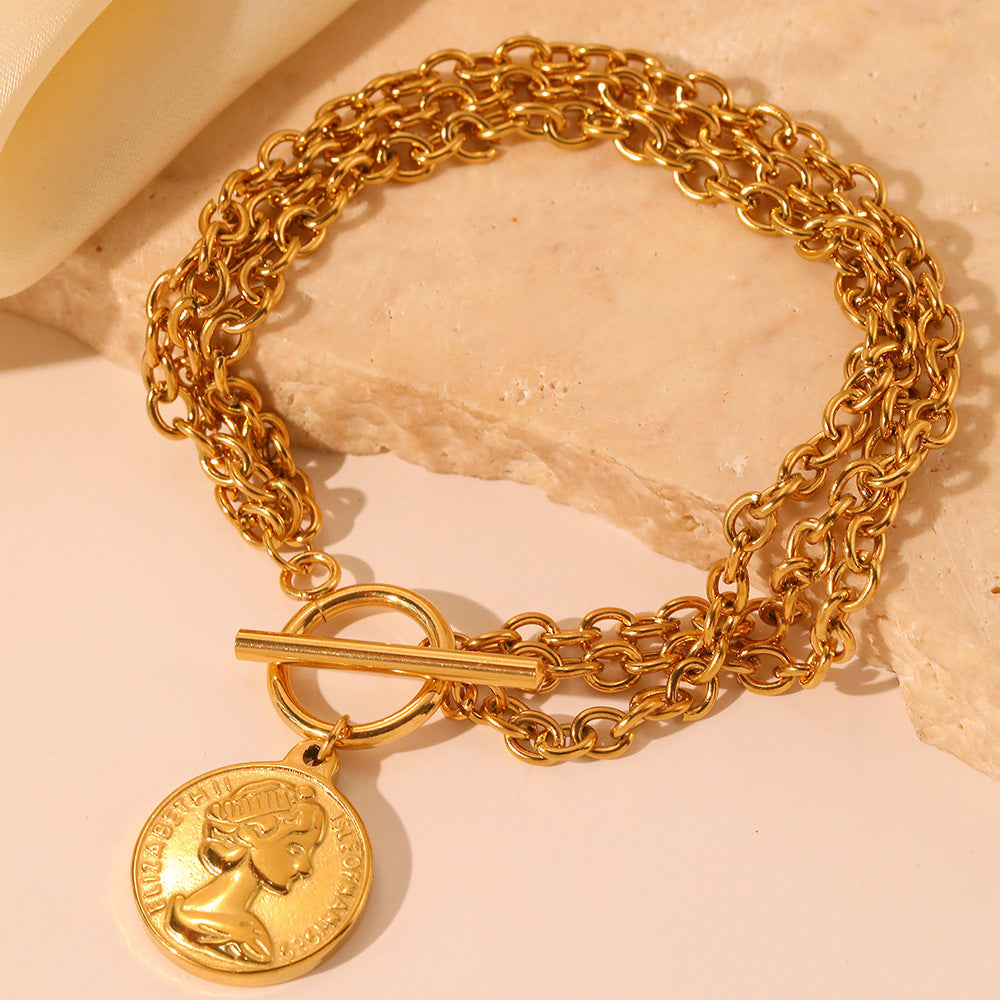 Multi-layered gold-tone chain bracelet featuring an OT toggle clasp and a round cameo coin pendant