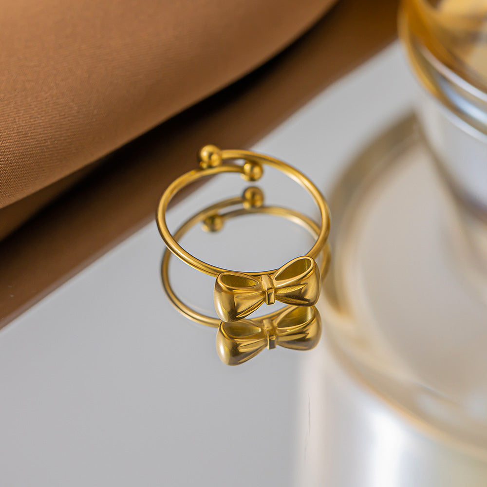 Golden ring featuring a polished bow motif and an open adjustable band.