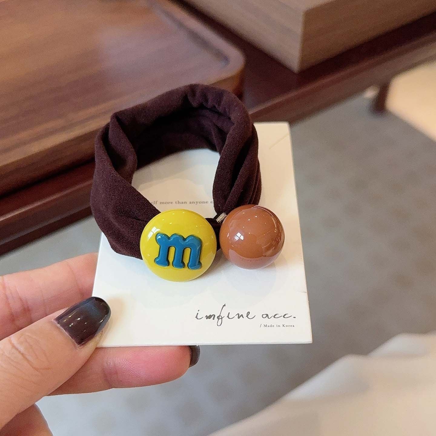 M&M candy bean hair tie with yellow bean charm on a dark brown band