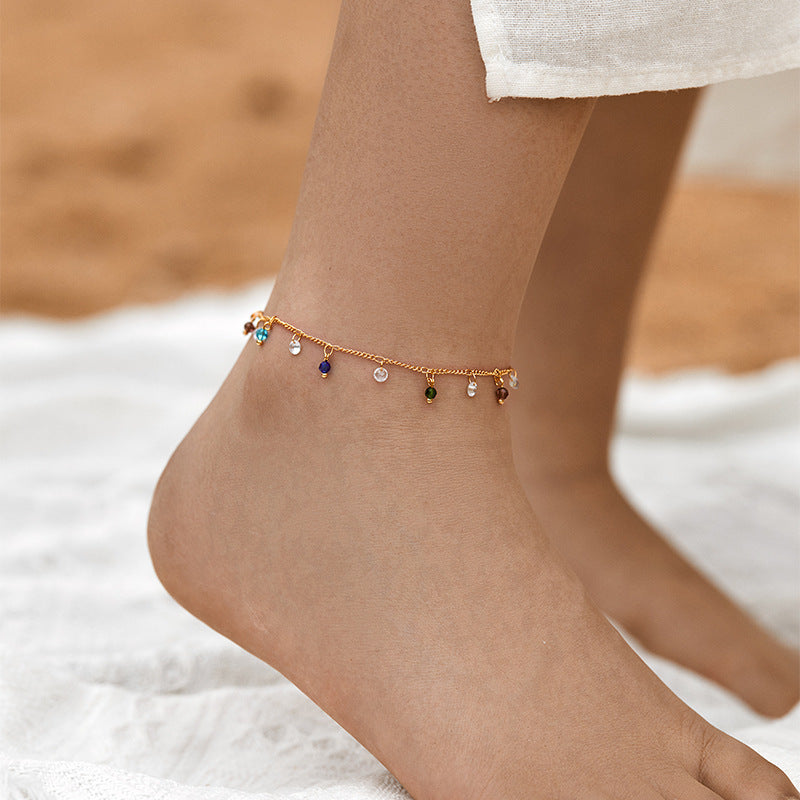 Gold-tone chain anklet featuring dangling multi-colored crystal charms