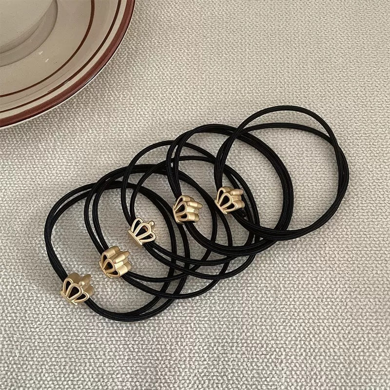 Black cord hair tie with a small gold-tone crown charm