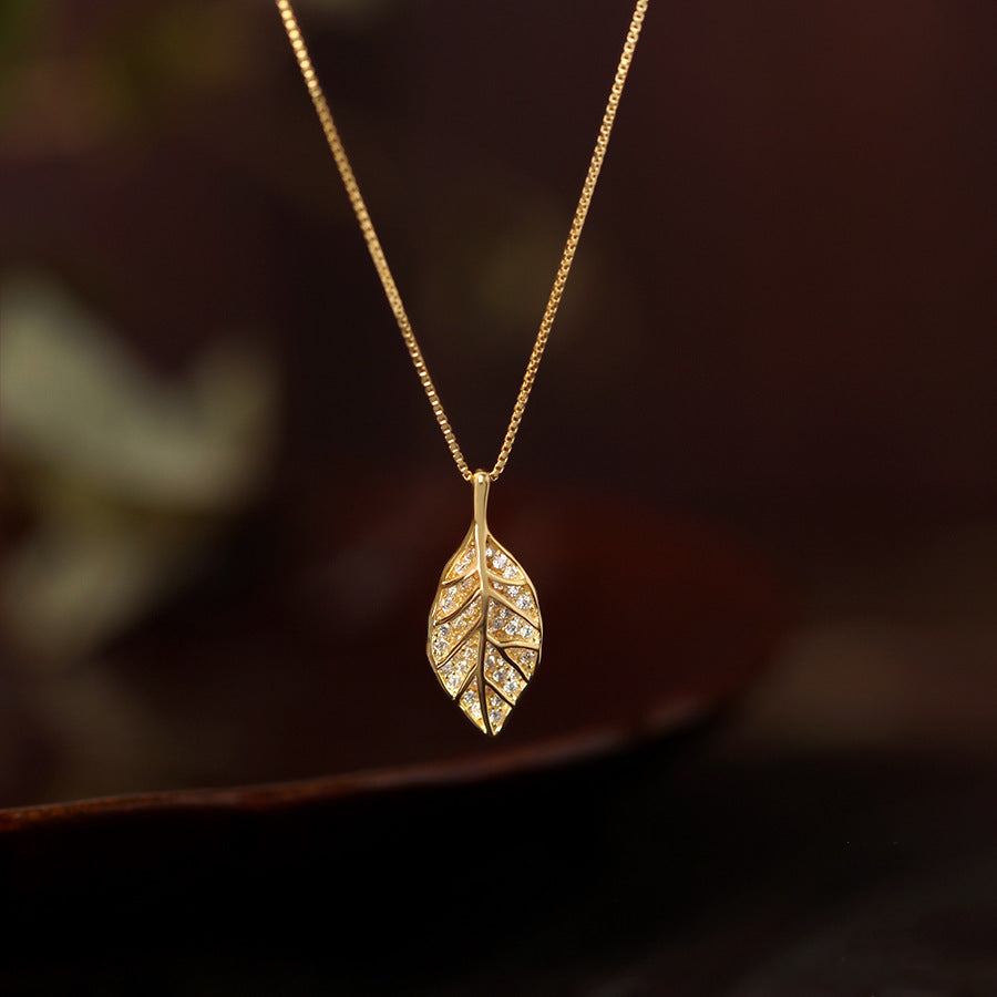 Gold leaf pendant necklace with crystal-set details on a delicate gold chain