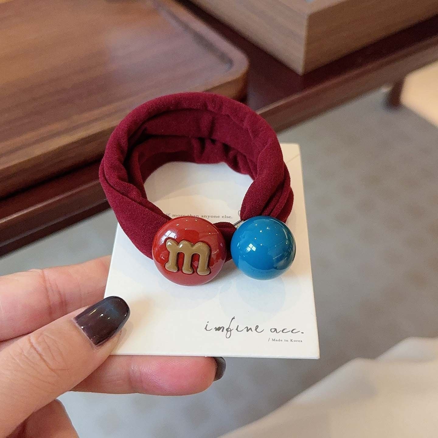 M&M candy bean hair tie with red bean charm on a wine red band