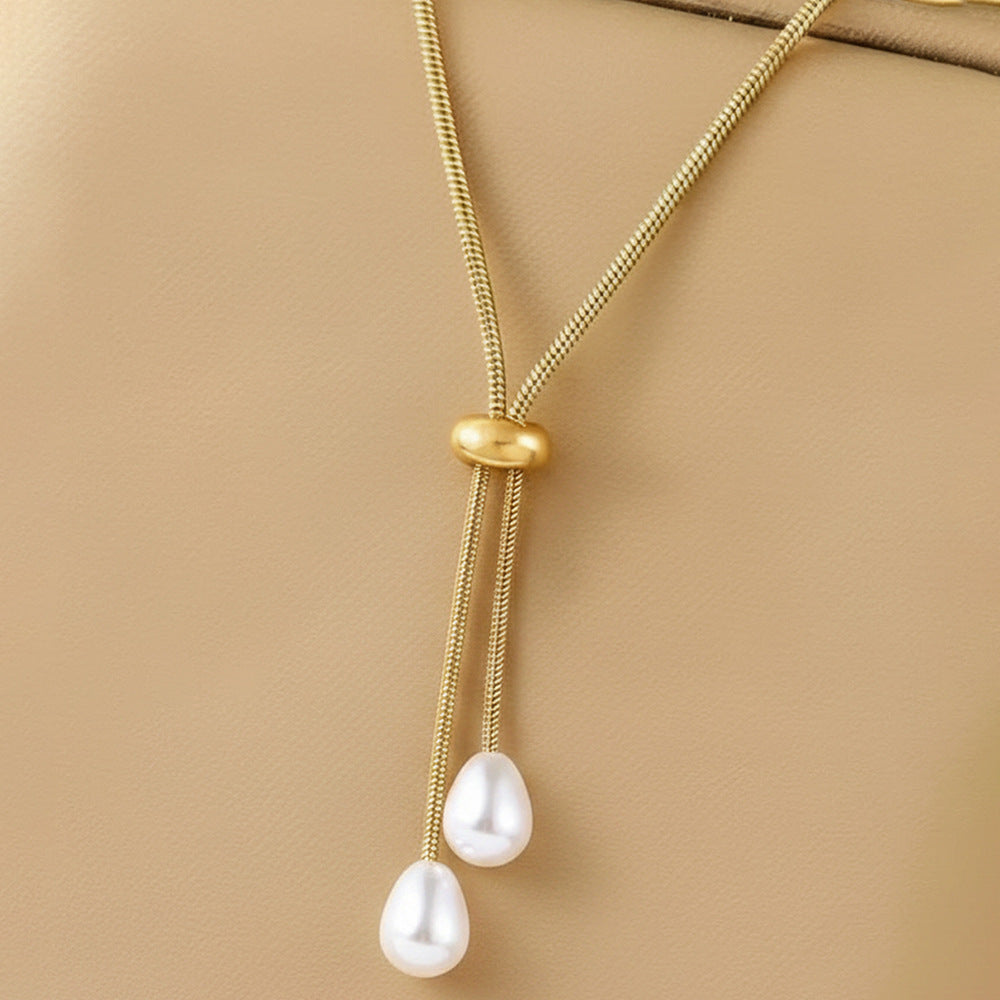 Golden lariat necklace featuring an adjustable chain with two hanging pearl-look drops